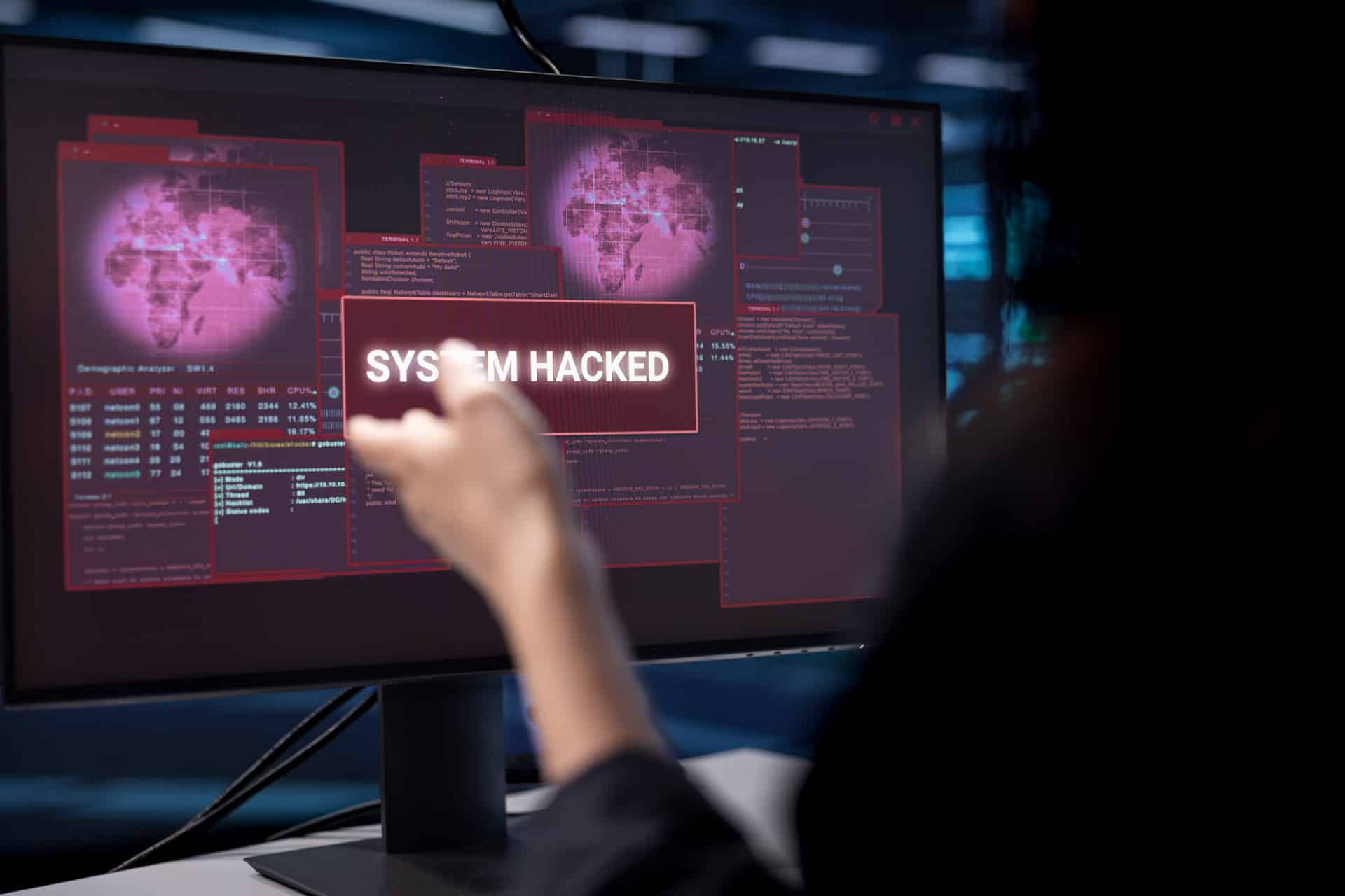Auf dem PC Bildschirm ist "System Hacked" zu sehen.